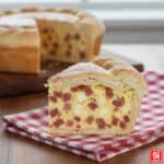 Fetta di Pizza Rustica Napoletana (Pizza Chiena) alta, con ripieno compatto di salame, prosciutto, scamorza e uova, perfetta per Pasqua e Natale.