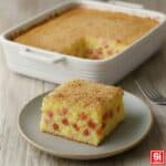 Gateau di patate napoletano in pirofila bianca con una fetta servita in primo piano per mostrare il ripieno di salumi e la gratinatura dorata.