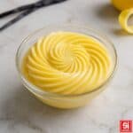 Crema pasticcera gialla in ciotola di vetro con spirale continua e texture vellutata