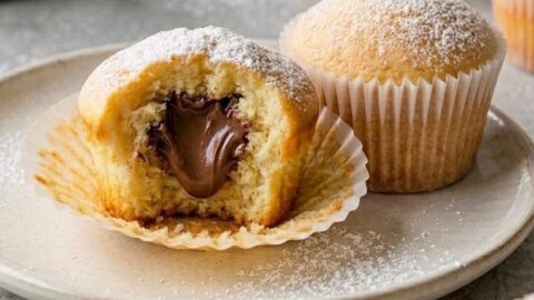 Muffin alla Nutella con cuore morbido visibile, fotografato in primo piano su piatto chiaro.