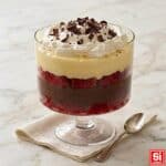 Zuppa inglese servita in coppa di vetro, con strati di pan di Spagna, crema pasticcera, cioccolato e panna montata.