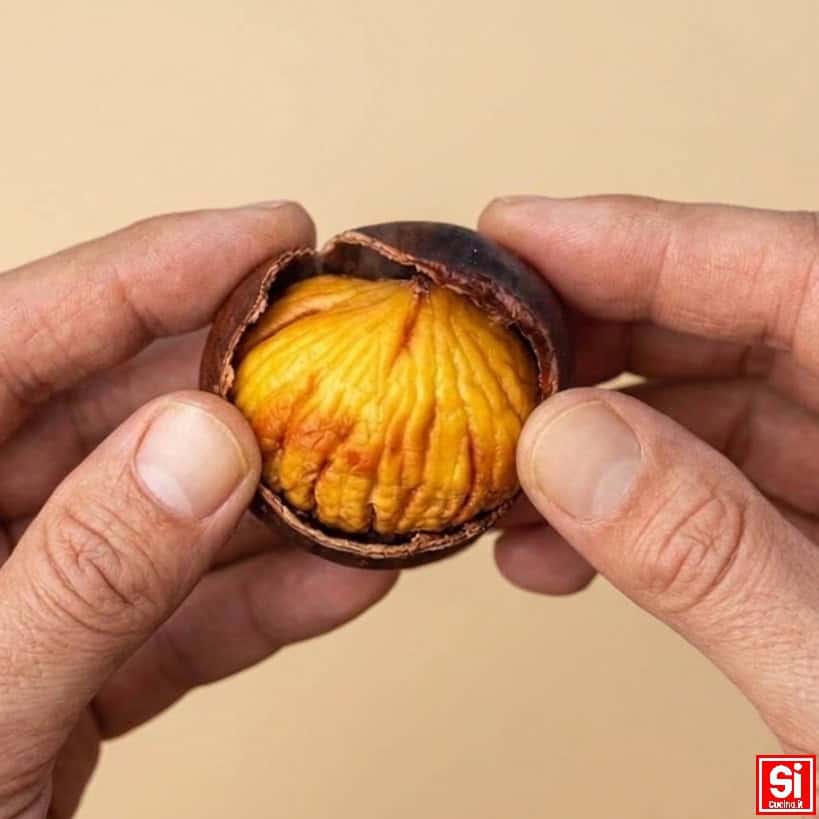 Mani che sbucciano una castagna cotta in friggitrice ad aria mostrando la polpa morbida e dorata